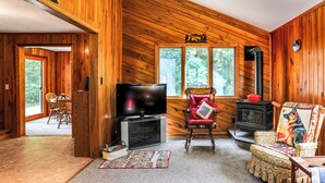 A wooden interior with a TV, fireplace, and two chairs.