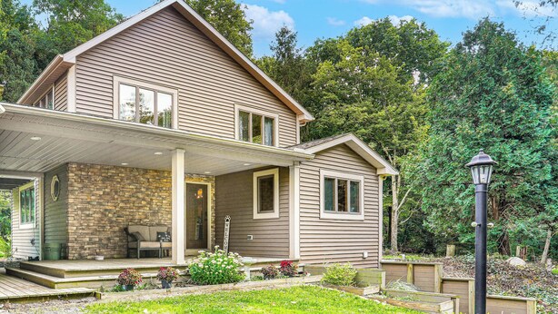 A two-story house with a stone porch, a covered entryway, and a landscaped garden.