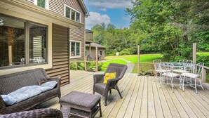 A deck with wicker furniture, a glass table, and chairs.