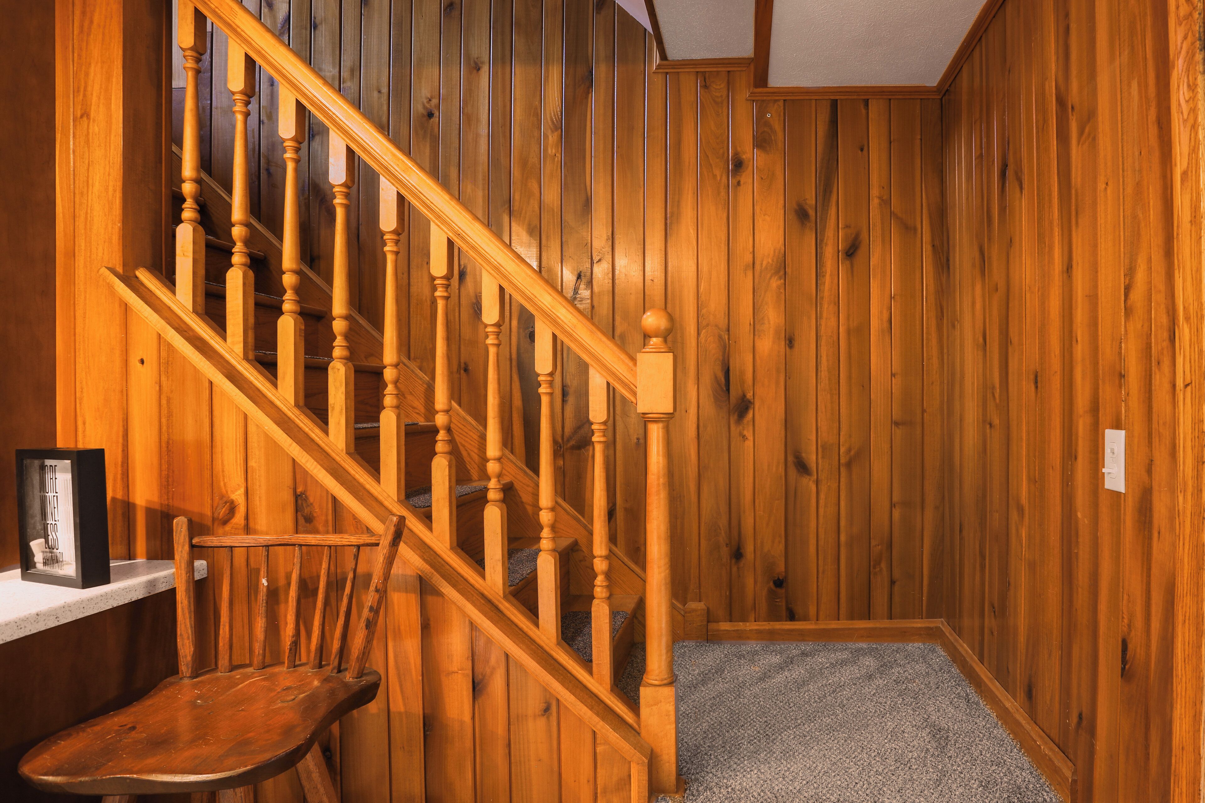 A wooden staircase with a chair and a picture frame on a shelf.