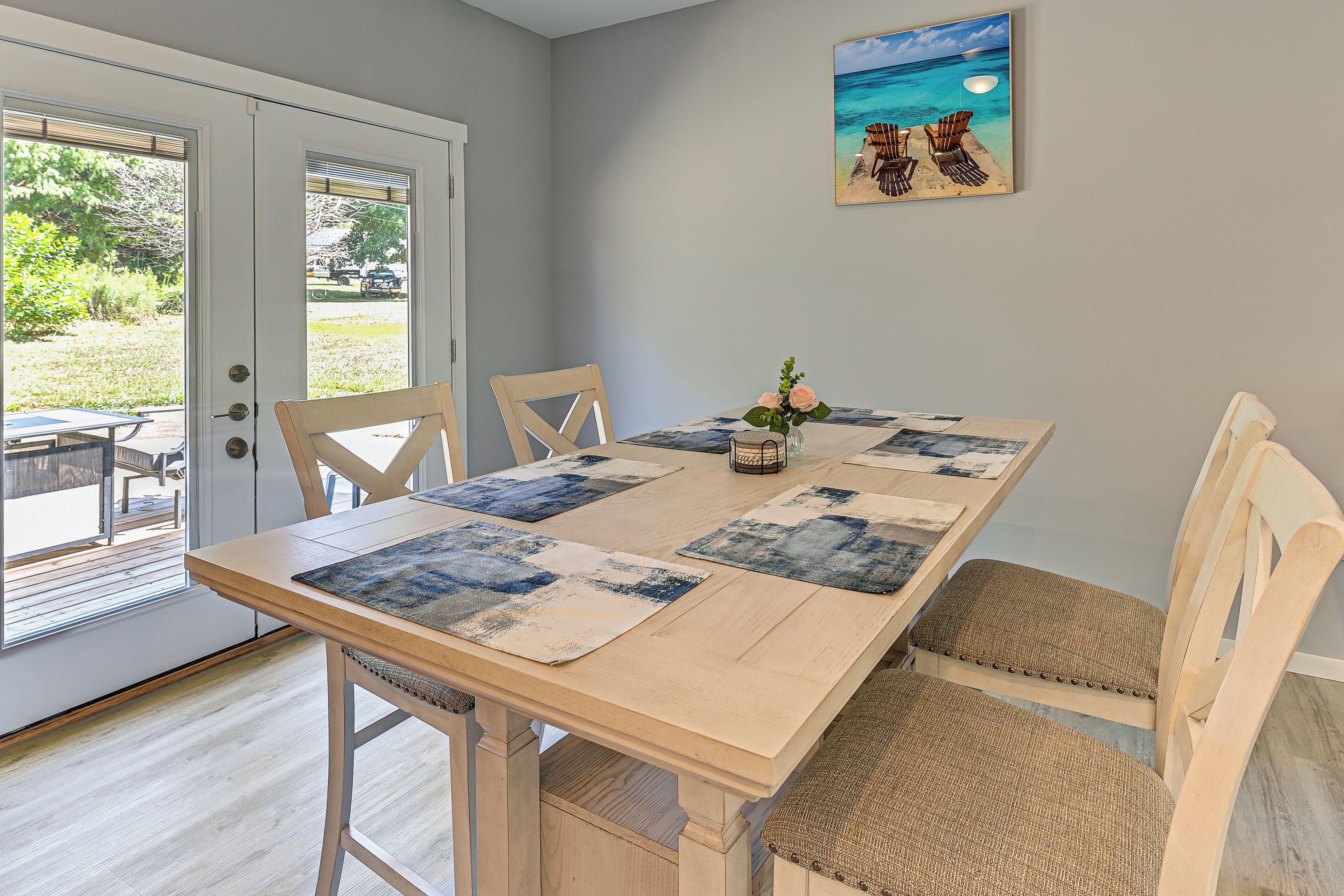 Un coin repas avec une table en bois, des chaises rembourrées et une vue sur une terrasse extérieure, accessible par une porte vitrée.
