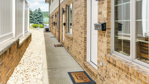 A brick building with a narrow pathway leading to a door with a doormat. - Townhome w/ Patio: 1 Mi to Clearfield Riverwalk (Clearfield)