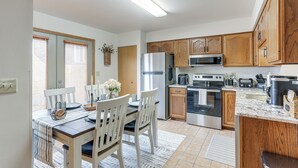 A modern kitchen with wooden cabinets, stainless steel appliances, and a dining area with white chairs and a table. - Townhome w/ Patio: 1 Mi to Clearfield Riverwalk (Clearfield)