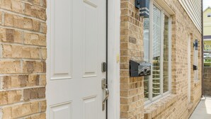 A brick building with a white door, a window with a metal frame, and a small black object mounted on the wall. - Townhome w/ Patio: 1 Mi to Clearfield Riverwalk (Clearfield)