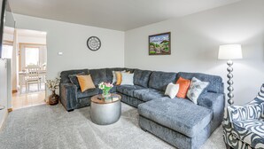 A living room with a grey sectional sofa, a round coffee table, a wall clock, and a painting. - Townhome w/ Patio: 1 Mi to Clearfield Riverwalk (Clearfield)