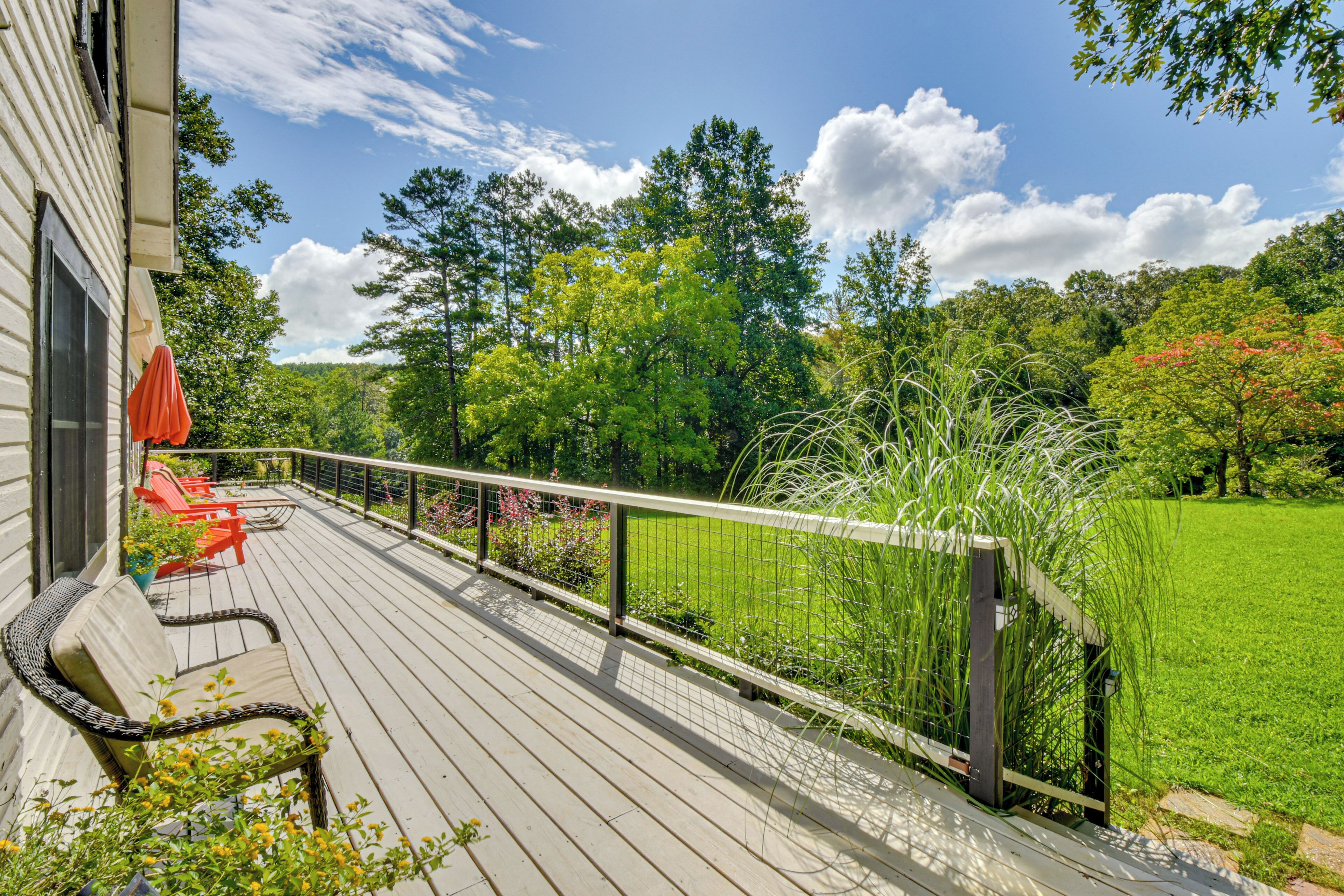 A wooden deck with outdoor seating and a view of a green lawn and trees.
