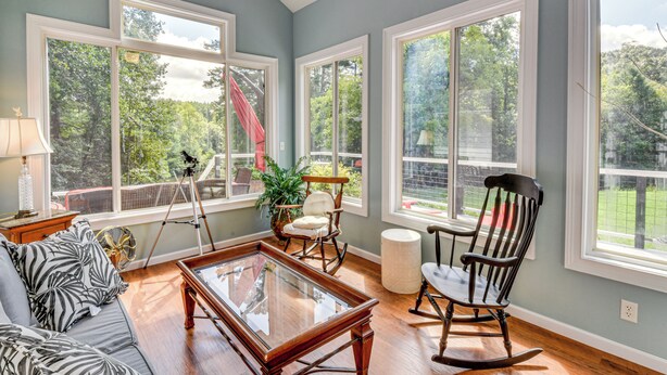 A spacious living room with large windows, a sofa, a rocking chair, and a coffee table. - 30 Acres & Pond: North Georgia Mtn Farmhouse (Demorest)