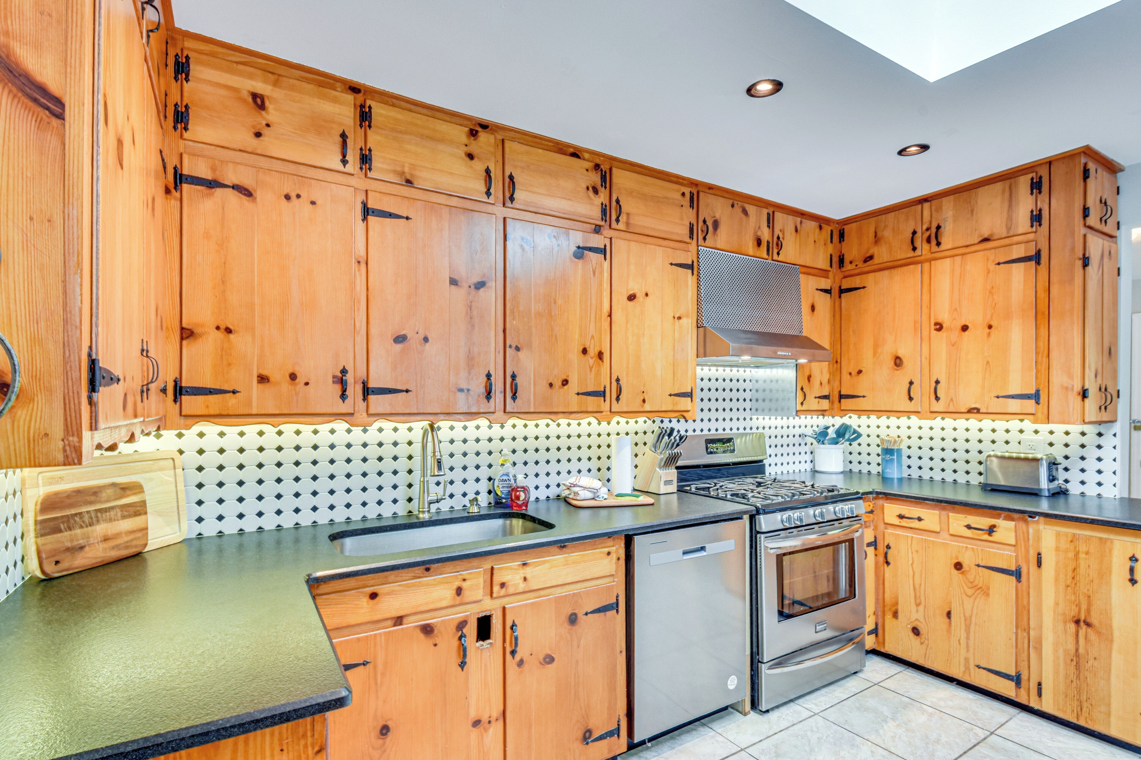 A kitchen with wooden cabinets, a stainless steel dishwasher, and a gas stove.