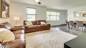 A spacious living room with a brown leather sofa, a white shag rug, and a dining area with a table and chairs. - Families Welcome, Fenced Yard: Inviting Greer Home (Greer)