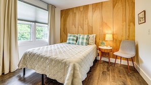 A bedroom with a bed, a chair, a nightstand, and a window with curtains. - Families Welcome, Fenced Yard: Inviting Greer Home (Greer)