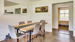 A dining area with a wooden table and grey upholstered chairs, a large mirror, and a painting on the wall. - Families Welcome, Fenced Yard: Inviting Greer Home (Greer)