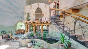 A spacious atrium with a central water feature, a wooden staircase, and various potted plants. - Taos Dome Home w/ Hot Tub, Fireplace + Mntn Views! (Arroyo Hondo)