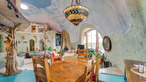 A rustic interior with a wooden dining table, chairs, a hanging stained glass light fixture, and a fireplace. - Taos Dome Home w/ Hot Tub, Fireplace + Mntn Views! (Arroyo Hondo)