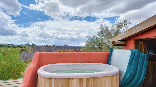 A hot tub on a wooden deck with a view of a natural landscape and a wooden fence. - Taos Dome Home w/ Hot Tub, Fireplace + Mntn Views! (Arroyo Hondo)