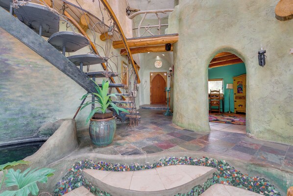 A spiral staircase with a potted plant, a tiled floor, and an arched doorway leading to another room.