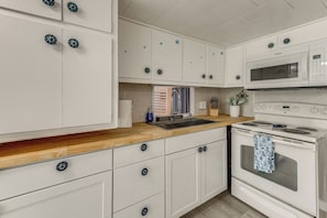 A kitchen with white cabinets, a microwave, an oven, and a wooden countertop. - Screened-in Patio: Home 2 Mi to Cortez Beach! (Bradenton)