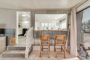 A dining area with two wooden chairs, a white table, and a view through a glass door. - Screened-in Patio: Home 2 Mi to Cortez Beach! (Bradenton)