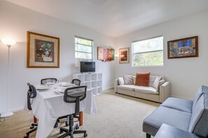 A living room with a dining table set for four, a gray sofa, a white couch, and a TV on a stand. - Walk to King Street Eats! Condo in Jacksonville (Jacksonville)