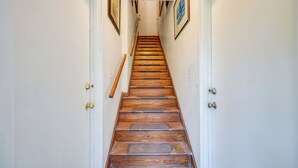 A wooden staircase with white walls and doors, leading to an upper floor. - Walk to King Street Eats! Condo in Jacksonville (Jacksonville)