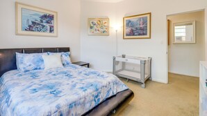 A bedroom with a bed, a crib, and three framed pictures on the wall. - Walk to King Street Eats! Condo in Jacksonville (Jacksonville)