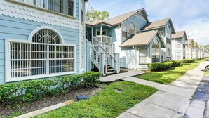 A row of light blue houses with white trim, a front porch, and a staircase leading to the entrance. - Florida Fun! Family Condo w/ Pool, 8 Mi to WDW (Kissimmee)