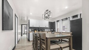 A modern kitchen with white cabinets, a black refrigerator, and a dining area with a wooden table and chairs.