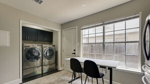 Une buanderie équipée d’un lave-linge, d’un sèche-linge et d’une table avec des chaises.