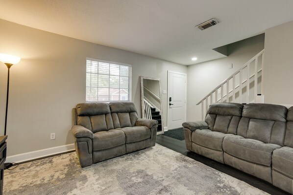 A living room with two leather sofas, a rug, a lamp, and a staircase leading to a door. - 4 Mi to Iah: Suburban Houston Townhome (Humble)