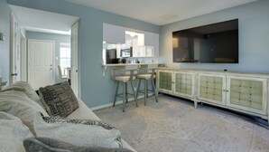 A living room with a sofa, a coffee table, and a kitchen area in the background.