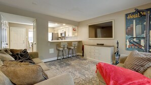 A living room with a beige sofa, a red throw blanket, and a kitchen area with a microwave and bar stools. - Near Airport & Interstate: Houston Area Townhome (Humble)