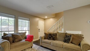 A living room with two beige couches, a red chair, and a patterned rug. - Near Airport & Interstate: Houston Area Townhome (Humble)