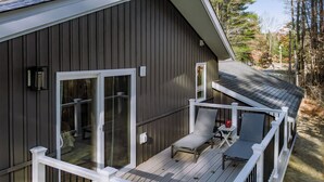 A deck with a white railing, a chair, and a table. - Modern Gem on 15 Acres, 5 Mi to Old Orchard Beach! (Saco)