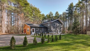 A two-story house with a large front yard, surrounded by tall trees. - Modern Gem on 15 Acres, 5 Mi to Old Orchard Beach! (Saco)