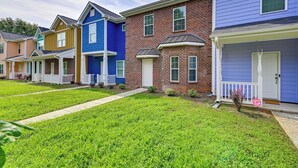 A row of townhouses with a front lawn and a stop sign.
