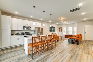 A modern kitchen with white cabinets, stainless steel appliances, and a wooden dining area.