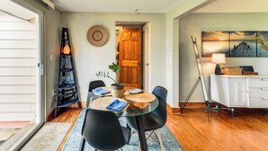 Un comedor con una mesa de vidrio, sillas negras, una puerta de madera y un cuadro en la pared.