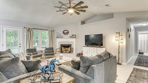 A living room with a fireplace, a ceiling fan, and a television. - 1 Mi to Zoo: 'rustic Bungalow' in Gulf Breeze! (Gulf Breeze)