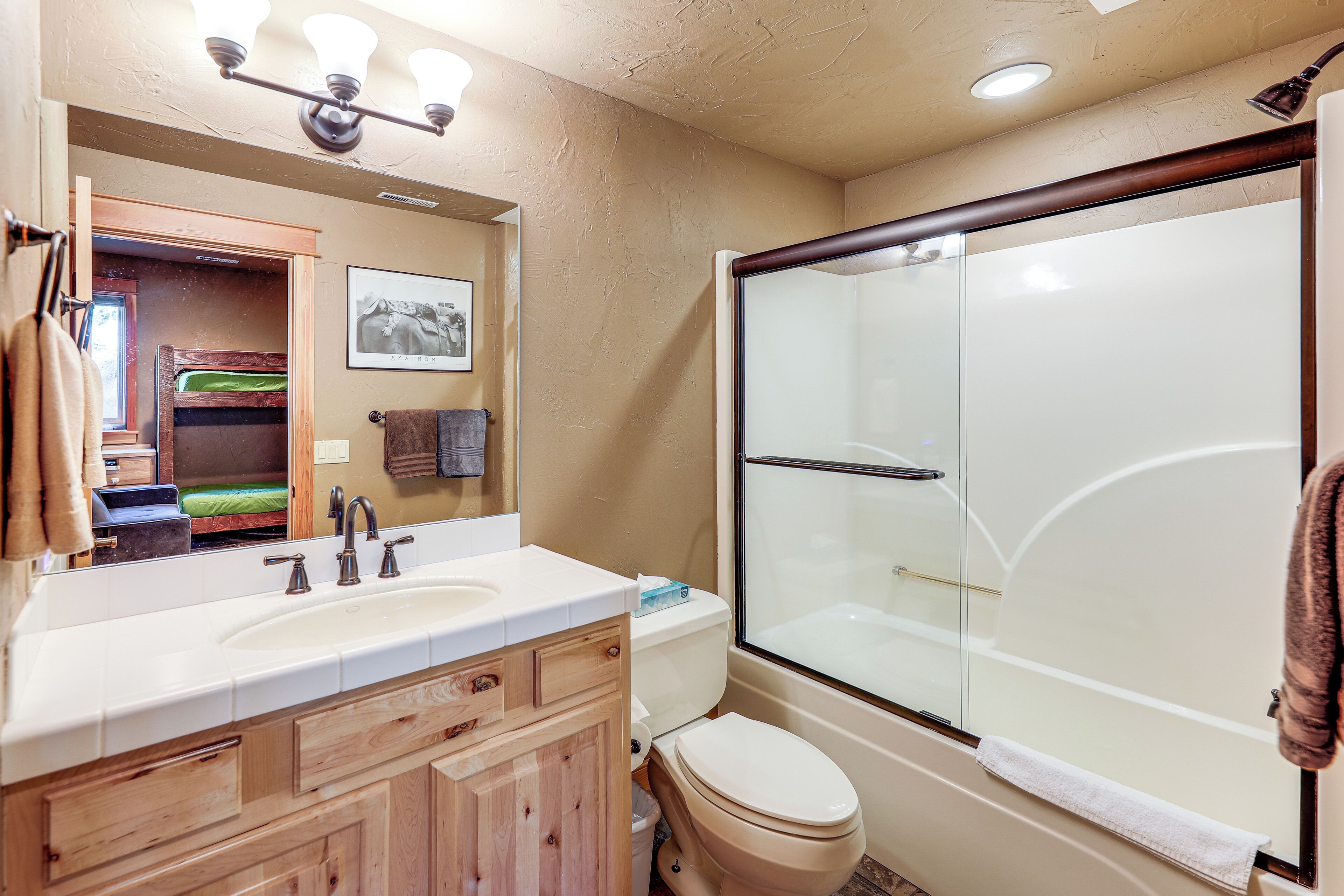 A bathroom with a wooden vanity, a sink, a toilet, and a glass-enclosed shower.