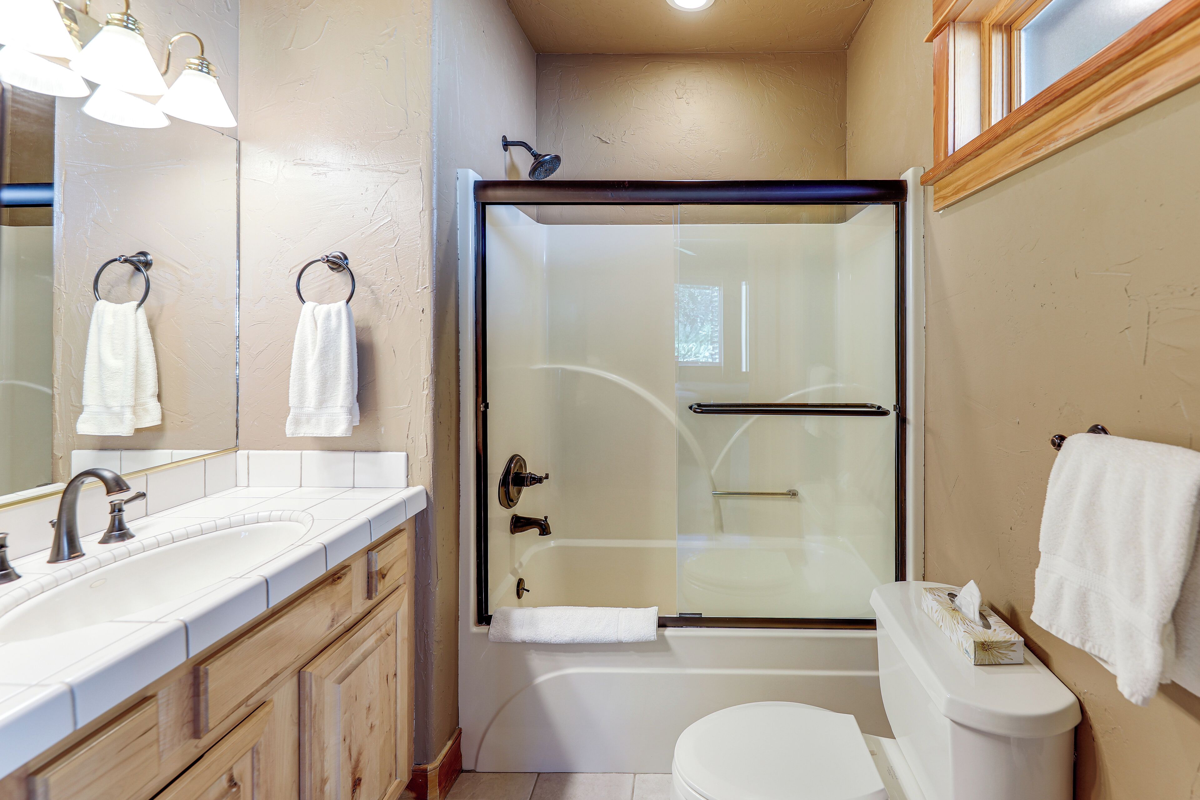 A bathroom with a glass-enclosed shower, a white sink, and a toilet.