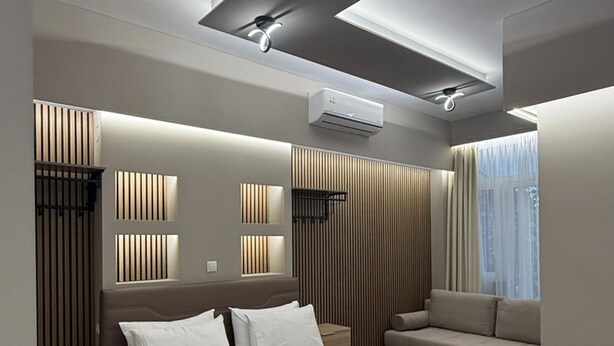 A modern bedroom with a large bed, a sofa, and built-in lighting. - Monastiraki 110 Superhost Hub (Athens)
