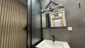 A modern bathroom with a white sink, a mirror, and a striped door. - Monastiraki 110 Superhost Hub (Athens)