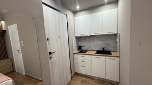 A compact kitchen with white cabinets, a wooden countertop, and a black sink. - Monastiraki 110 Superhost Hub (Athens)