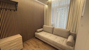 A modern living room with a beige sofa, wooden panel wall, and a small wooden cabinet. - Monastiraki 110 Superhost Hub (Athens)