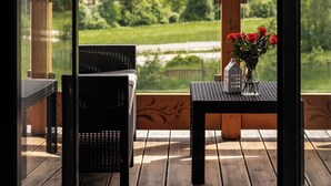 A balcony with wicker chairs and a table, overlooking a mountainous landscape with greenery and a village below. - IJG Imperial Apartamenty Szymaszkowa (Zakopane)