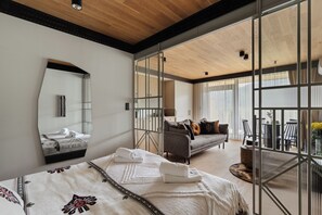 A modern hotel room with a large bed, a sofa, a dining area, and a balcony with a view. - IJG Imperial Apartamenty Szymaszkowa (Zakopane)