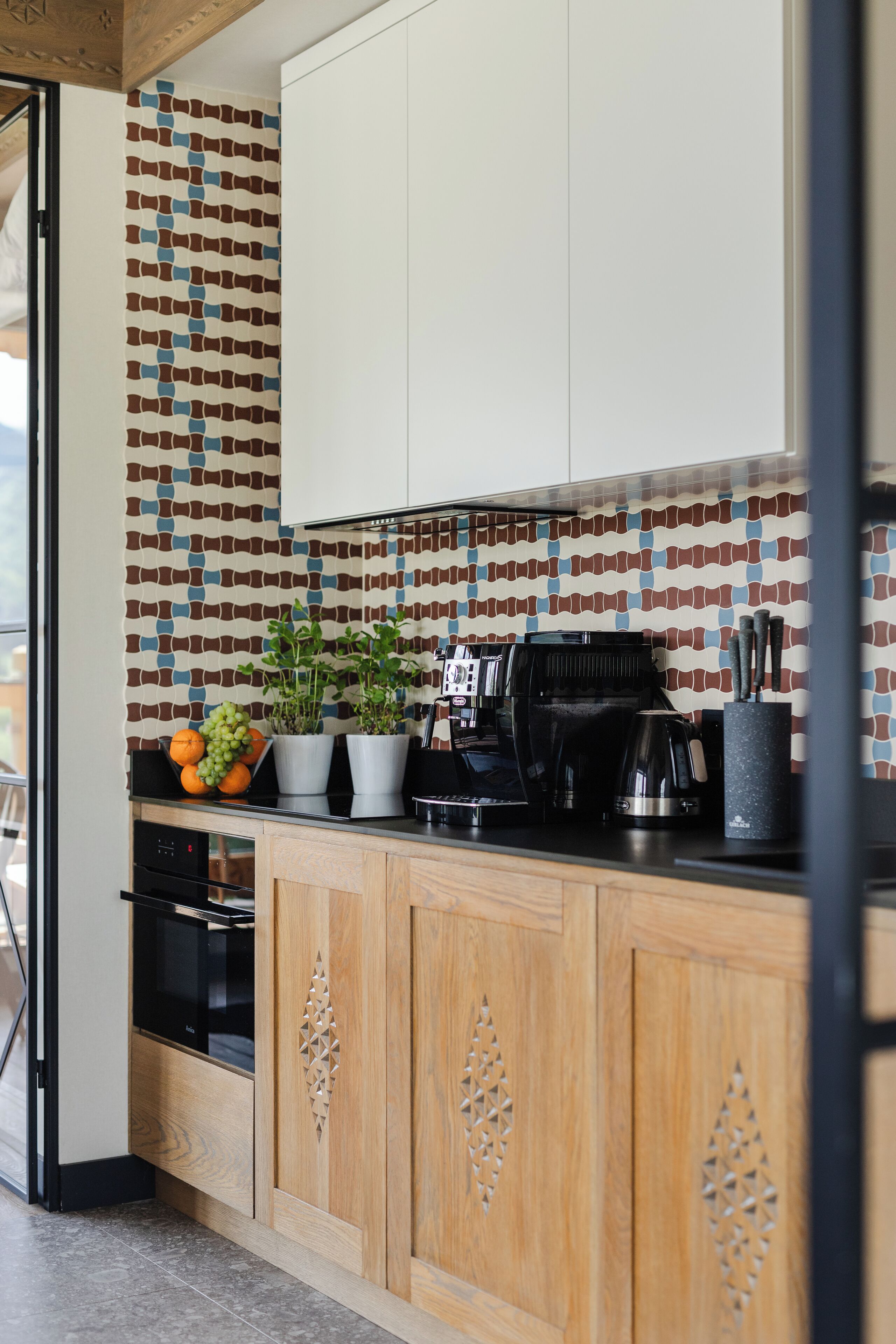 A modern kitchen with wooden cabinets, a patterned backsplash, and a coffee maker on the counter.