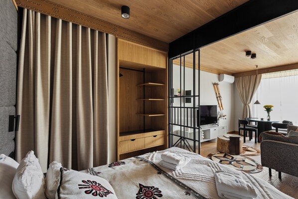 A modern hotel room with a large bed, a wooden wardrobe, a desk with a computer, and a view of the city through large windows. - IJG Imperial Apartamenty Szymaszkowa (Zakopane)