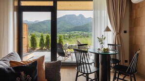 A room with a view of mountains, a dining table with chairs, and a sofa with cushions. - IJG Imperial Apartamenty Szymaszkowa (Zakopane)