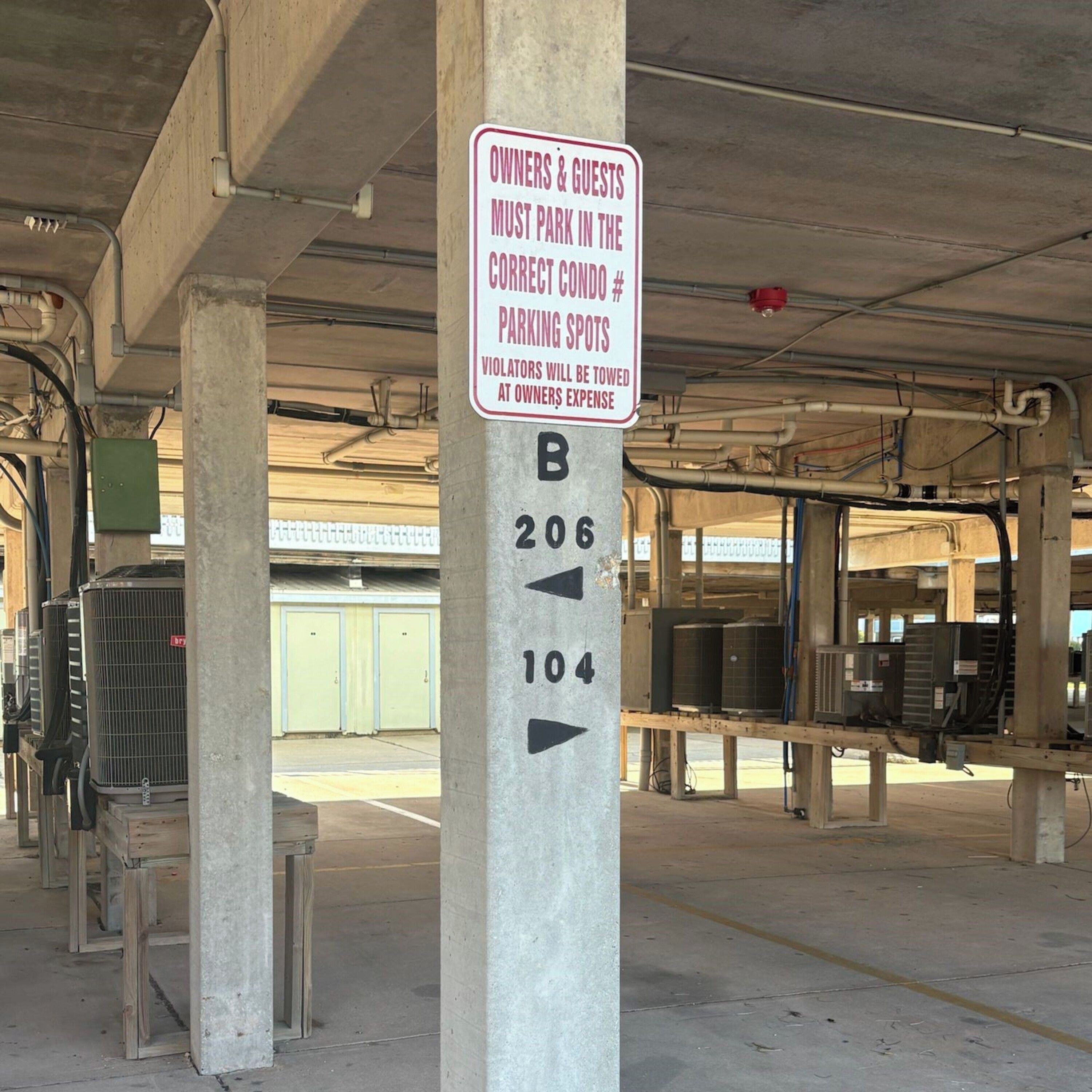 A parking sign with directions to parking spots B206 and B104, and a warning that violators will be towed at the owner's expense.