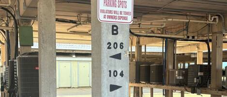 A parking sign with directions to parking spots B206 and B104, and a warning that violators will be towed at the owner's expense.